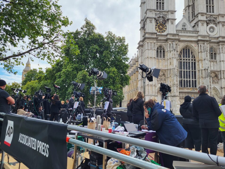 People standing on a platform with camera equipment in front of westminster abbey during live broadcasting at the state funeral of queen elizabeth ii