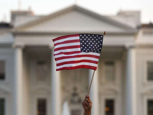 United States flag being waved by hand in front of White House in Washington DC